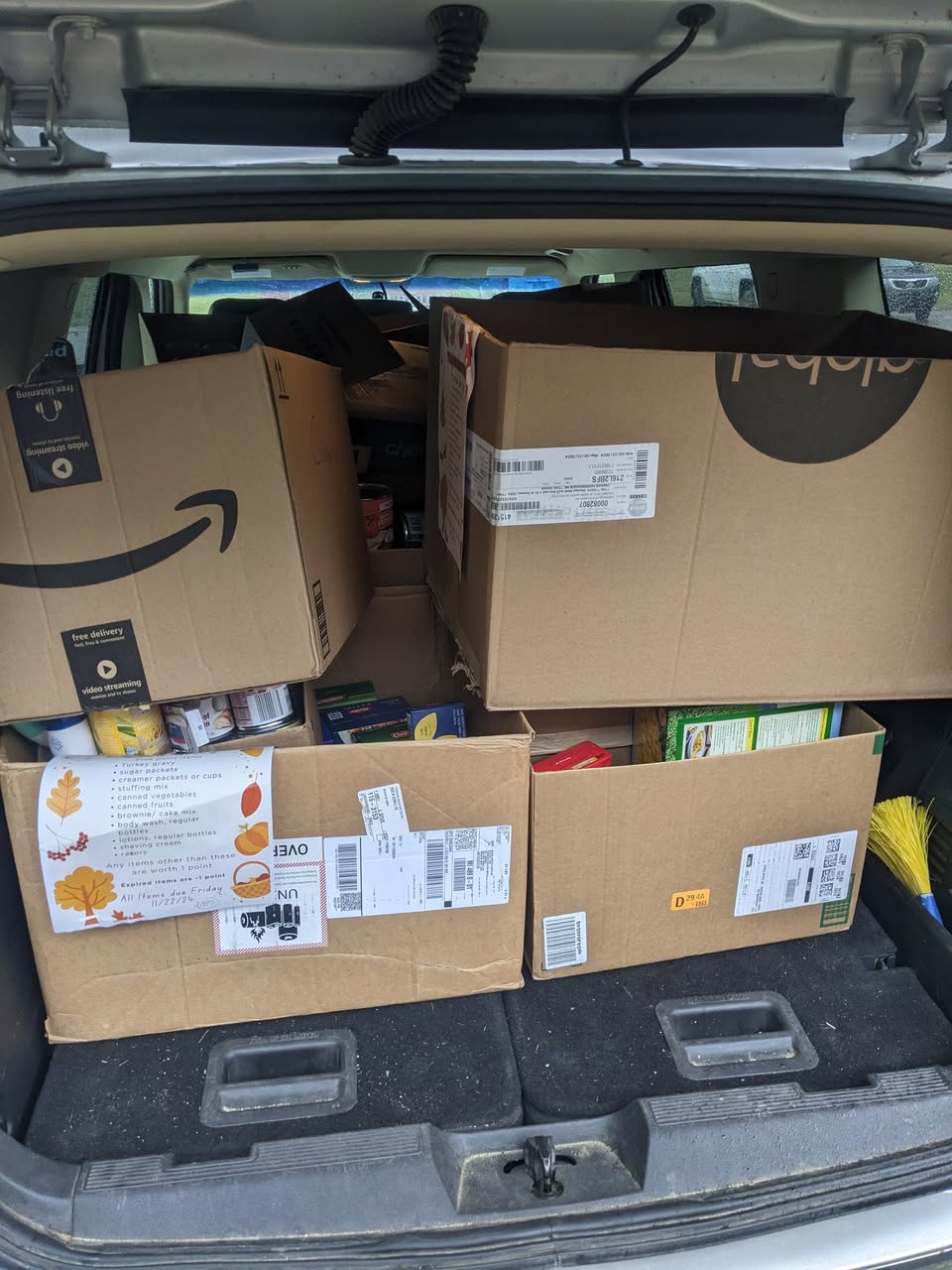 Boxes filled with canned goods and non-perishable food being loaded into a vehicle.